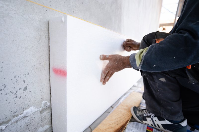Workers installing rigid foam insulation on the side of a building (Photo by Miljan Živković - adobe.stock.com)